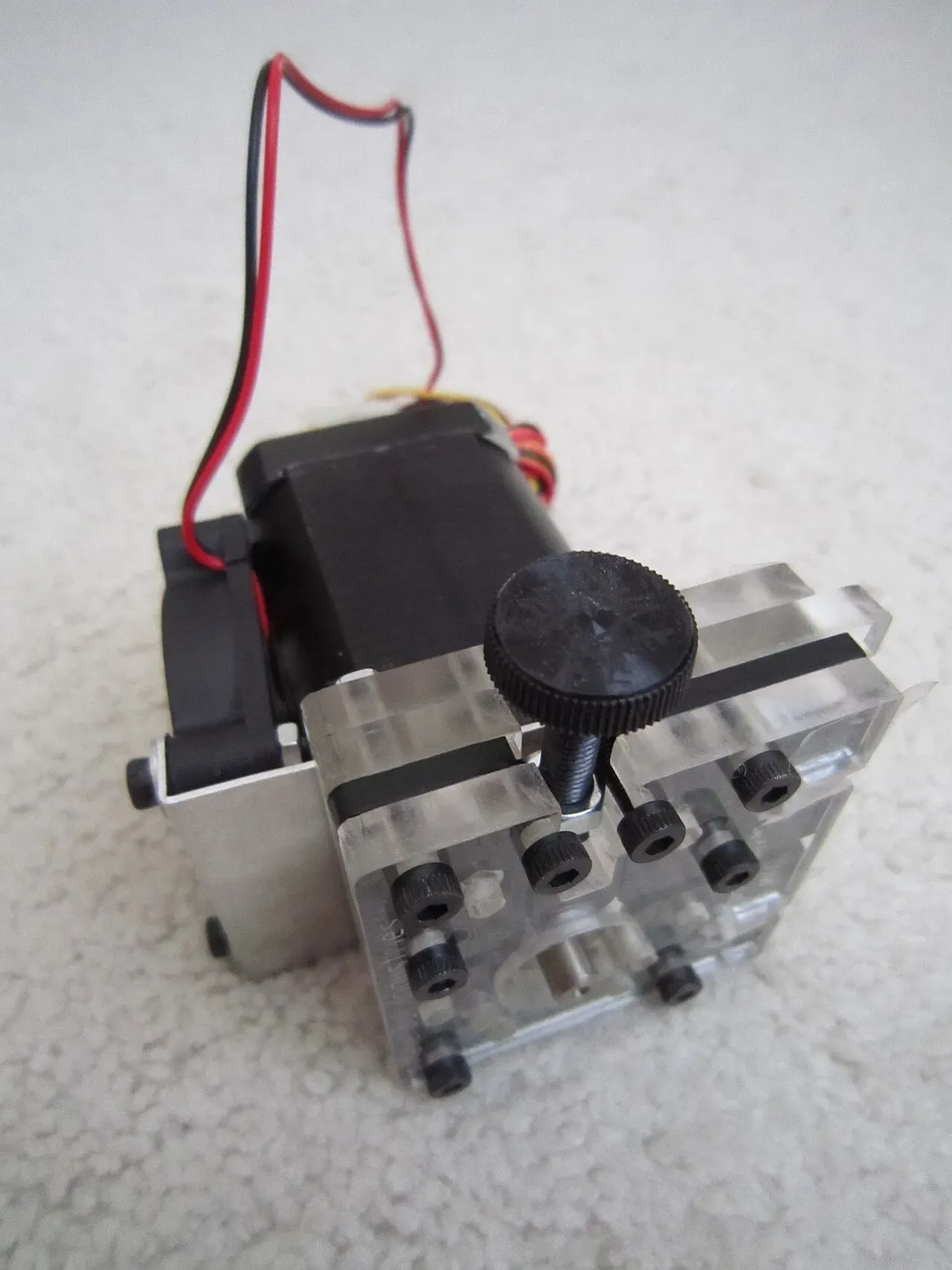 An extruder stepper motor with a black tension knob