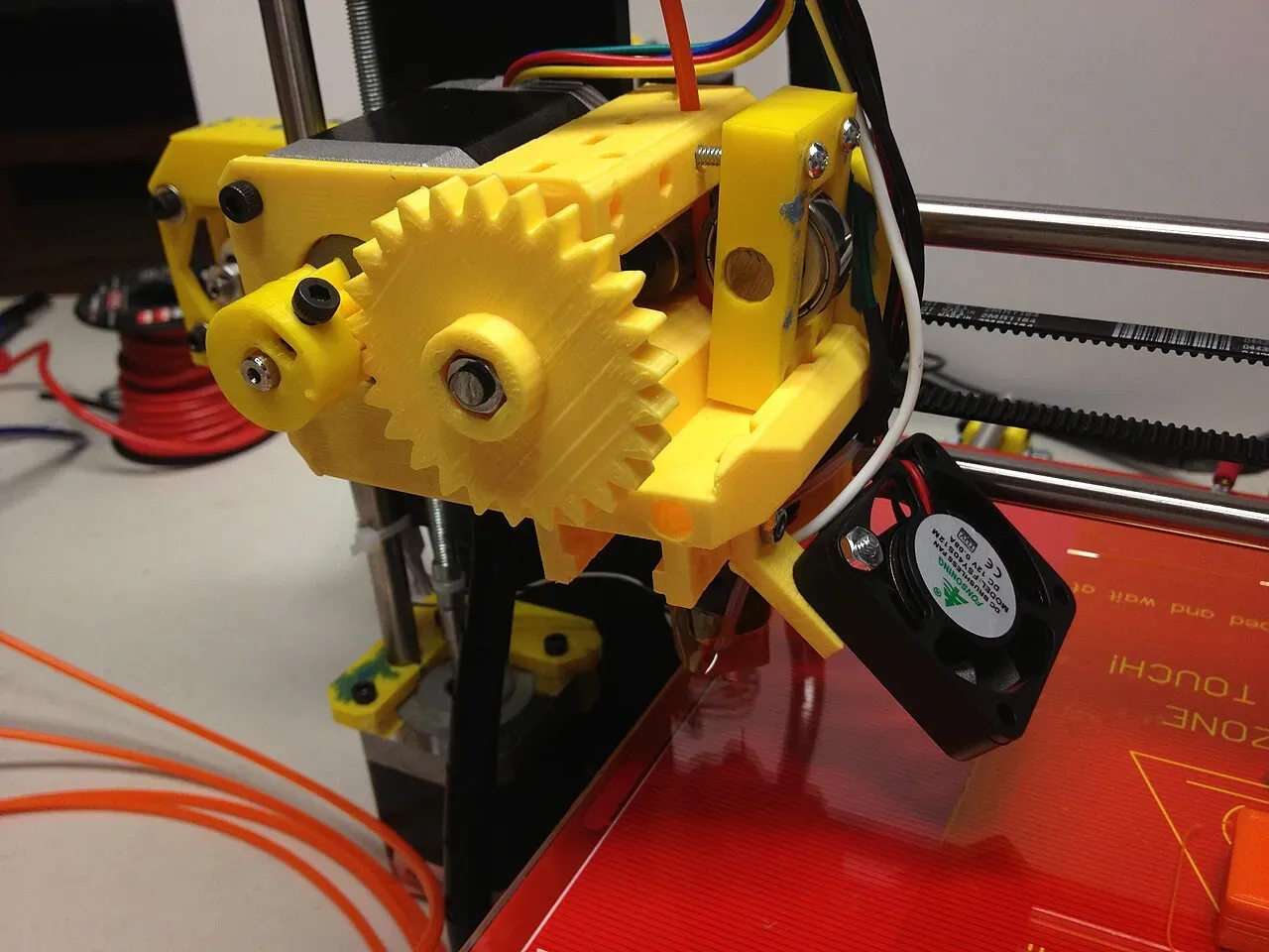 A yellow printed geared extruder on a Prusa i3
