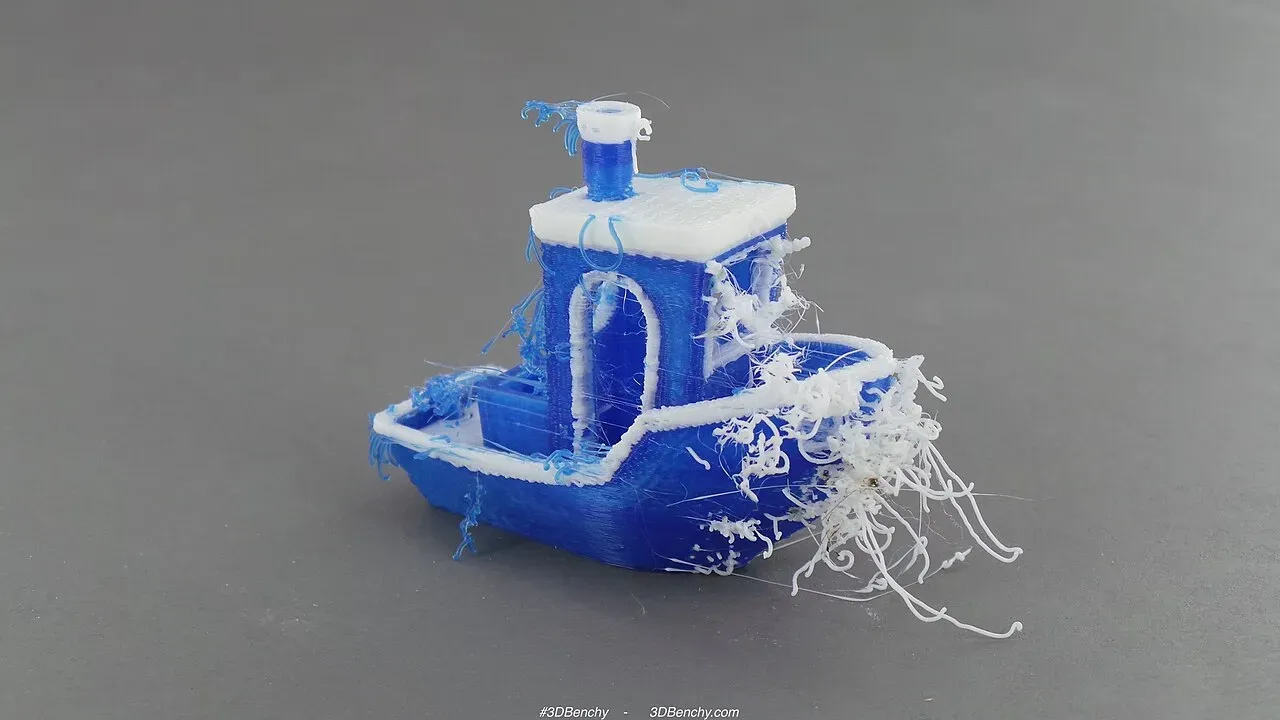 A two-colour Benchy boat with white strings of plastic across it