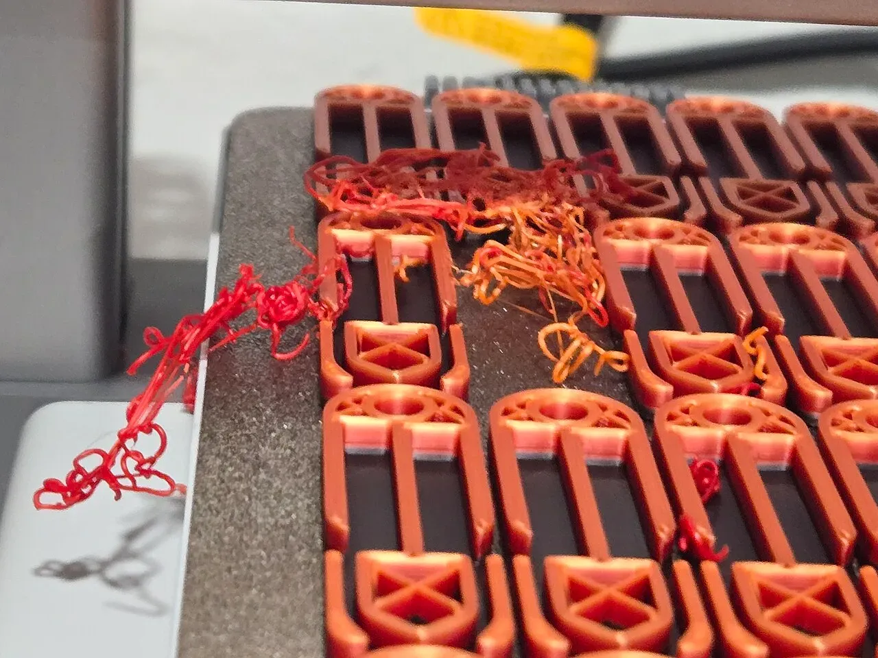 A plate of red parts with stringy blobs of plastic on top