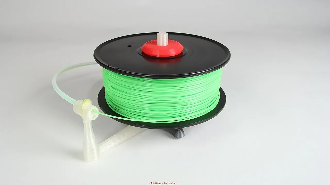 A green filament spool on a printed stand-alone spool holder