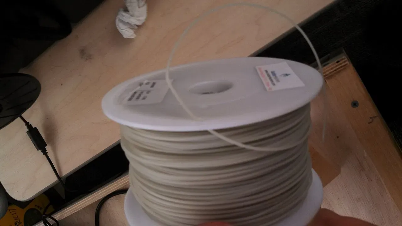 A spool of natural PLA filament on a shelf