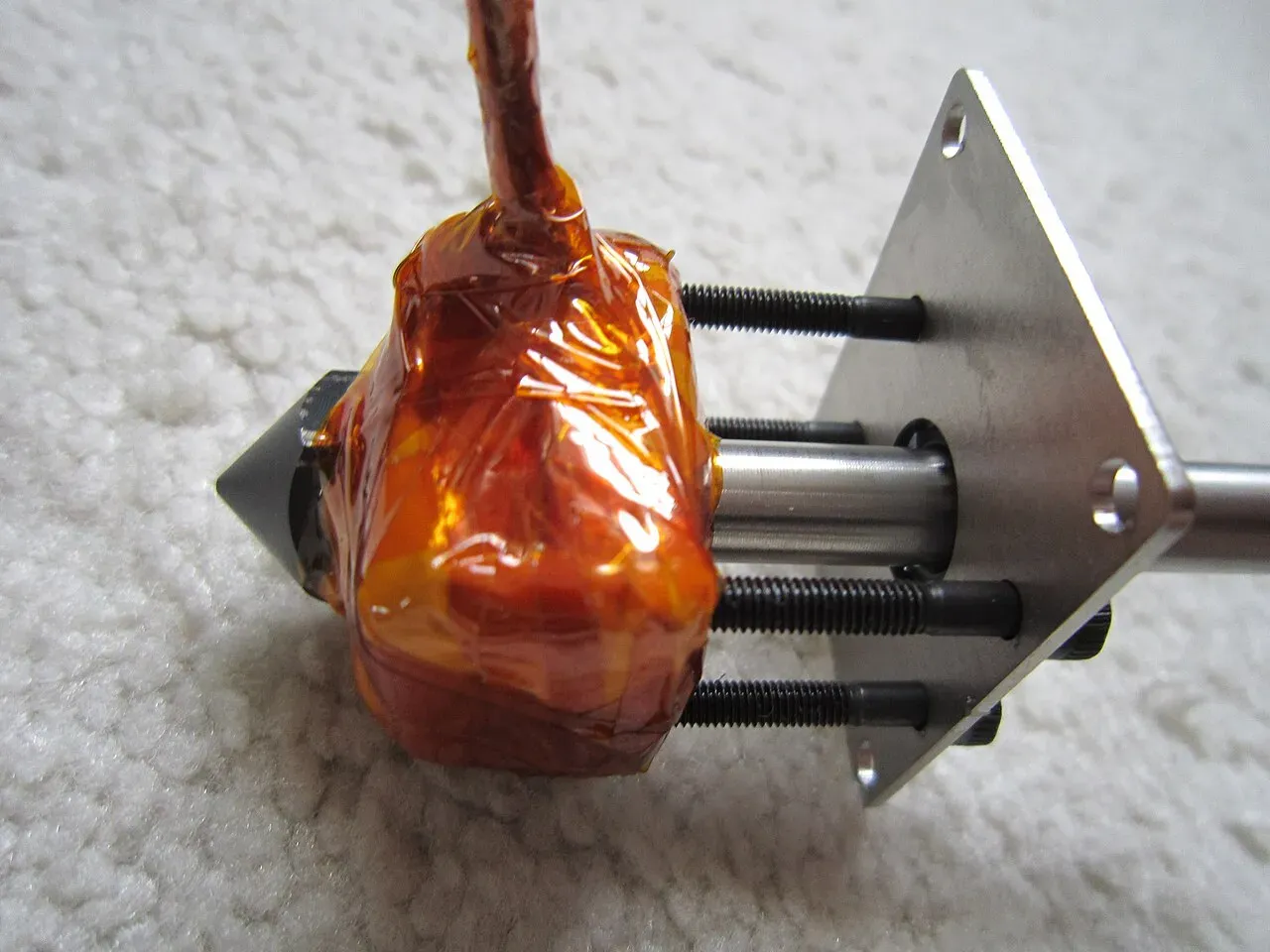 A homemade hotend wrapped in Kapton tape on its mount