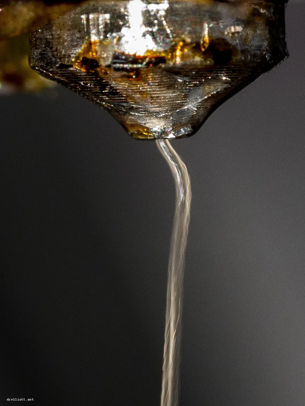 Close-up of a nozzle extruding a thread of clear plastic