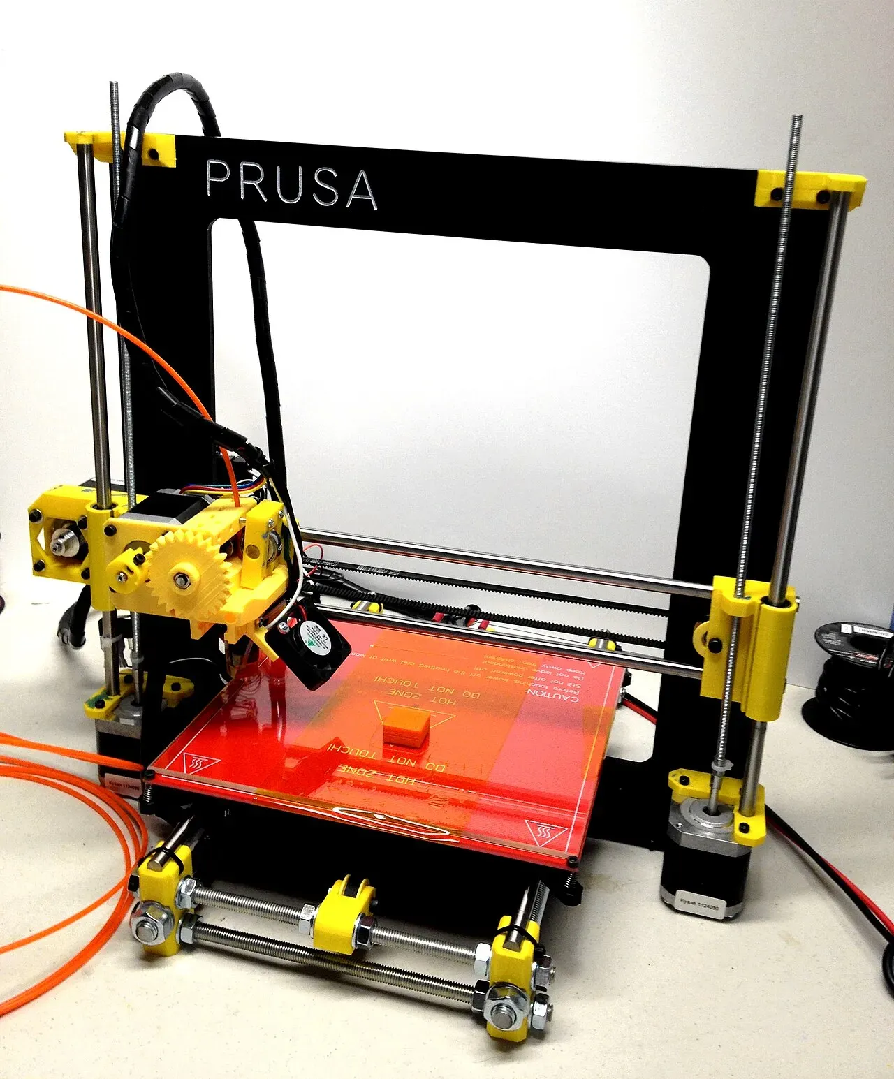 A complete Prusa i3 printer with a red heated bed
