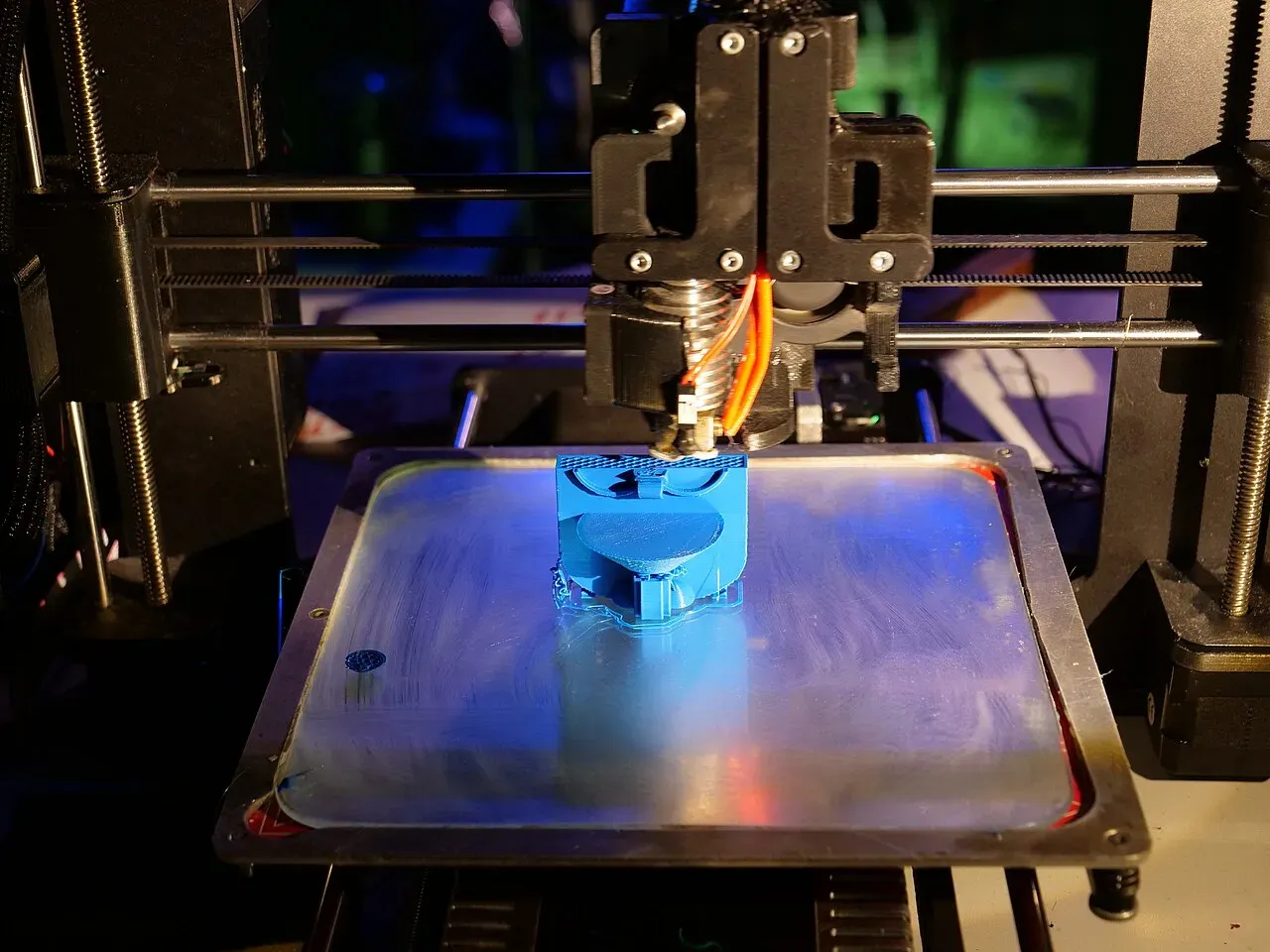 A blue part printing on a metal bed