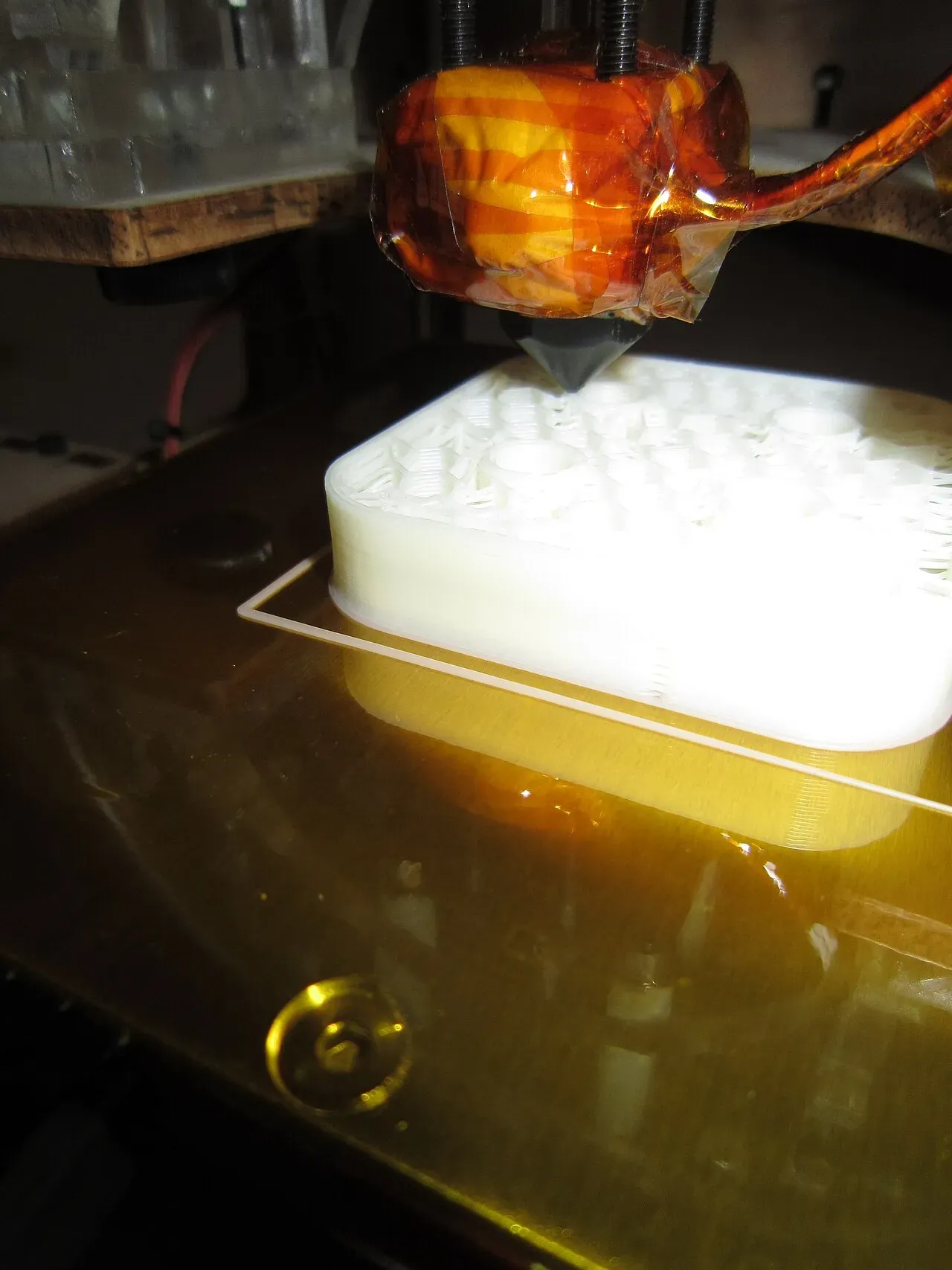 A part printing on a heated bed, first layers visible